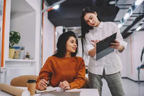 年轻有吸引力的熟练女工在 Coworking 空间协作过程中分析文件夹中的信息 有才华的女学生准备一起参加即将到来的校园考试 — 图库照片