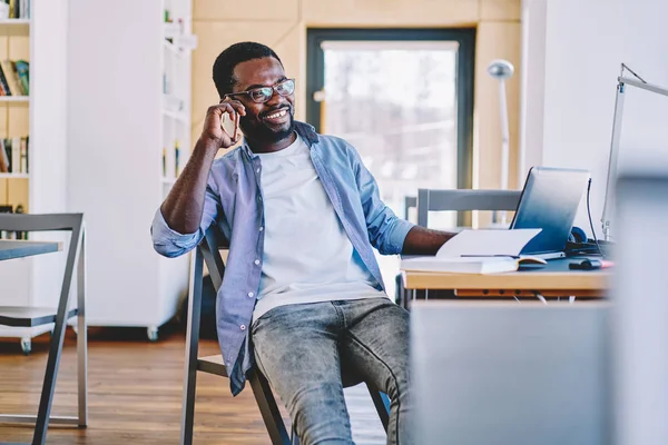 Fröhlicher Dunkelhäutiger Millennial Typ Der Während Seines Fernjobs Schreibtisch Telefoniert — Stockfoto