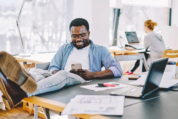 Fröhliche Afrikanisch Amerikanische Büroangestellte Sitzt Entspannt Schreibtisch Und Chattet Smartphone — Stockfoto