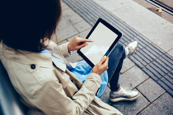 Cropped top view of young woman with finger typing text on modern tablet with blank screen for your advertising website content.Hipster girl choosing app on digital touch pad with copy space area