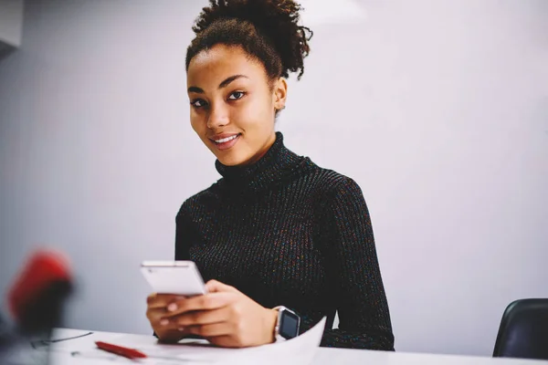 非洲裔美国员工微笑着看着在办公室工作场所拿着智能手机的相机的肖像 年轻的黑皮肤女学生使用手机聊天和在校园里建立社交网络 — 图库照片