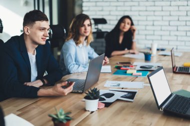 Seçici odak üzerinde özenli öğrenci dinleme meslektaşım modern ofiste beyin fırtınası toplantısı. Formal giyim teamworking modern ofis dizüstü bilgisayarları kullanan gençlerin Grup