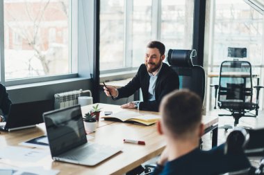 Formal giyim çalışma planı toplantısı sırasında kendi şirket çalışanı ile tartışırken gülüyor neşeli erkek gurur CEO'su. Pozitif patron ofiste iş toplantısı sırasında girişimciler ile konuşmak