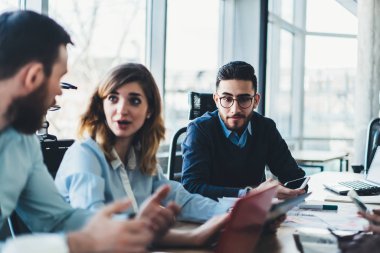 Grup akıllı genç insan birbirleriyle iletişim kurmak ve office brifing sırasında işbirliği süreci tartışıyor. Resmi erkek ve kadın çalışanların çalışma planı hakkında konuşurken aşınma