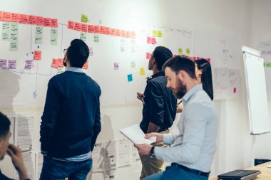 Genç insan resmi profesyonel takım giymek office duvarda yapışık renkli metin notları kullanarak proje oluşturma konusunda işbirliği. Ders sırasında çıkartmaları yabancı kelimeleri öğrenme öğrenci grubu