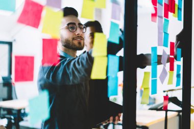 Renkli çıkartmalar ofis iç işbirlikçi işlemi sırasında cam duvara yapıştırılmış yabancı kelime öğrenme yetenekli gençlerin çeşitli takım. Yapışkan Not kullanan çok kültürlü öğrenciler
