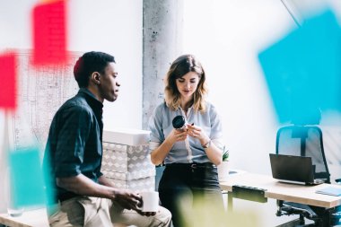Erkek ve kadın çok kültürlü çalışanların çalışma yer kahve molası sırasında başlangıç projesi tartışmaya formal giyim giymiş. Çeşitli iş arkadaşları birbirleriyle Cam ofis duvarının arkasında konuşmak