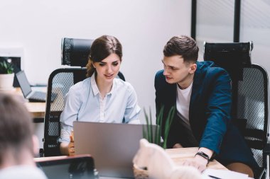 Öğretici Web sitesinde izliyor ve çalışma planı üzerinde modern dizüstü cihaz kablosuz internet bağlantısı ile tartışırken kadın ve erkek arkadaşları. İki BT geliştiricileri app ofisi işbirliği yükleme