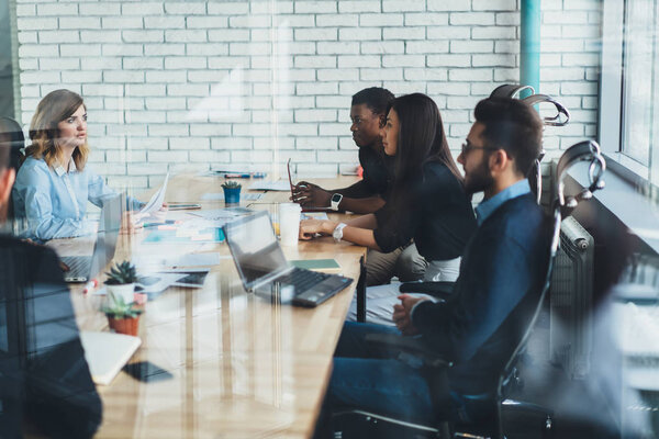 Совместный процесс современных разноплановых сотрудников во время мозгового штурма за стеклянными стенами.
