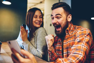 Mutlu bir evlilik Internet piyango sonuçları kazanan ile Smartphone cep telefonu ile çevrimiçi yayını izlerken zaferini kutluyor. Online açık artırma Web sitesinde telefon bahis kazanmak ile hayrete hipsters merak
