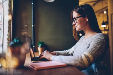Neşeli öğrenci ders için metin bilgi modern dizüstü bilgisayar klavyede girmeye yan görünüm bağlı 4 g kablosuz internet. Kadın grafik tasarımcı netbook uzaktan çalışma