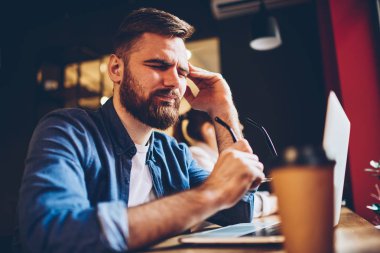 Yorgun genç profesyonel geliştirici yorgun dijital netbook aygıt anda overworking BT. Hayal kırıklığına uğramış sakallı öğrenci birçok sorunları ve dizüstü bilgisayar sabit çalışmaları nedeniyle baş ağrısı vardır