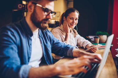 Portre pozitif kadın hipster blogger dinleme müzik çalma listesindeki kulaklık üzerinden bağlı Smartphone'a erkek uzaktan kablosuz 4 g kullanarak dizüstü bilgisayar çalışma sırasında internet cafe