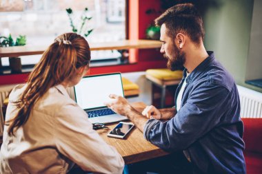 Meslektaşım boş ekran alanı ile Laptop uygulama hakkında açıklayan sakallı genç adam. İki erkek ve kadın tasarımcılar gelişmekte olan Web sitesi birlikte netbook çalışmak için yaratıcı fikirler tartışıyor