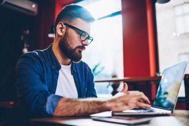 Düşünceli erkek serbest meslek yüksek hızlı internet bağlantısı ile modern dizüstü bilgisayarlara yeni antivirus kurma. Grafik tasarımcı uzaktan çalışma alanı coworking netbook klavye sakallı