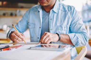 Ahşap masa kafede oturan sırasında araçlarını kullanarak akıllı yaratıcı erkek tasarımcı çizim yeni çizimler ve resim kırpılmış. Yetenekli adam mimar dikkatle planları kalem ve kural oluşturma