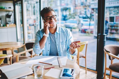 Telefon konuşma bir arkadaşım smartphone aygıtında sırasında gülüyor neşeli hindu erkek mimar. İş yerinde coworking içinde okul sırası sırasında cep telefonu tasarım projesi tartışmaya olumlu hindu delikanlı