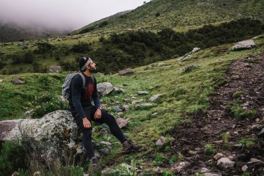 Rüya gibi genç adam yolcu etkin aşınma ve geri bir taş üzerinde oturan ve uzak yüksek Dağları'nın doğal sahne zevk seyir sırt çantası. Sırt çantası ile turist sonu yürüyüş sırasında üzerinde Salcantay vardır