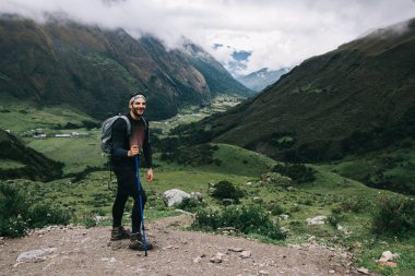Mutlu deneyimli genç adam turist trek dağlarda trekking çubukları kullanarak hiking zevk zevk aktif giyim giymiş. Salkantay üzerinde tırmanma sırt çantası ile pozitif gezgin