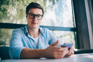 Gözlük vizyon düzeltme ödeme online ücretsiz 4 g internet bağlantısı kullanarak smartphone aygıt üzerindeki olumlu beyaz blogger portresi. Neşeli hipster adam cep telefon app güncelleme