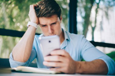 Kötü haber modern smartphone ile SMS mesajý okurken ağlıyor depresif genç adam. Video blog 4 g internet bağlantısı kullanarak dijital telefon üzerinde izlerken endişeli hipster öğrenci