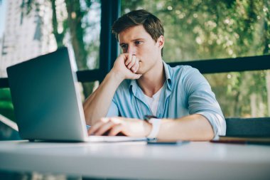 Kahve dükkanında kablosuz Internet bağlantısı kullanarak modern dizüstü bilgisayar web sitelerinde online video izlerken dalgın beyaz delikanlı. Netbook alan coworking içinde çalışan erkek serbest meslek