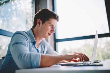 Düşünceli erkek bu geliştirici sohbet online modern dizüstü cihaz kablosuz bağlantı kullanarak. Genç adam serbest gelişmekte olan internet web siteleri bilgisayardaki uzaktan üzerinde konsantre