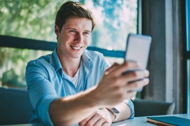 Modern smartphone ön kameraya gülümseyen ve selfie fotoğraf yayın için 4 g kullanarak blog yapma olumlu hipster adam Internet. Neşeli erkek blogger alarak resim gülüyor