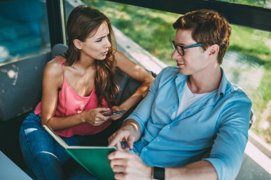 Genç ders kitabı-eğitim testi kız arkadaşı ile tartışırken hangi smartphone takipçileri ile sohbet online işaret eden adam akıllı. Kızgın genç kadın cafede oturan hipster adam ile anlaşmazlık vardır