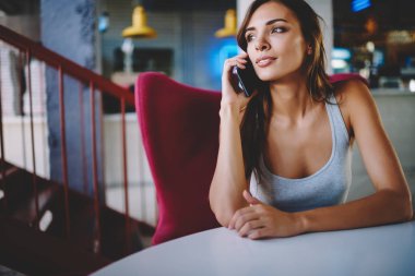 Uzakta yüksek hızlı mobil bağlantı kullanarak Smartphone'da çağrılırken arayan genç kadın büyüleyici durulması. İşleci ile digital kafede oturan hücresel konuşmak çekici hipster blogger