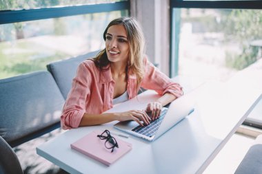 Neşeli kadın freelancer gülüyor ve internet sitelerinde arama bilgi modern dizüstü cihazda klavye tarafından bakarım. Uzaktan çalışma dijital netbook olumlu genç kadın