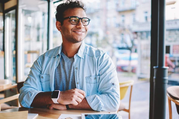 Good looking intelligent successful businessman in glasses for better vision pondering about creative ideas for startup project.Positive male person spending time in coffee shop sitting at table