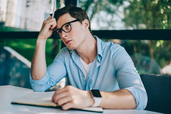 Gözlük vizyon düzeltme düşündüğüm edebiyat yayın yazmak için yaratıcı fikirler için düşünceli hipster öğrenci. Ders çalışma alanı coworking oturan planlama yetenekli genç adam durulması