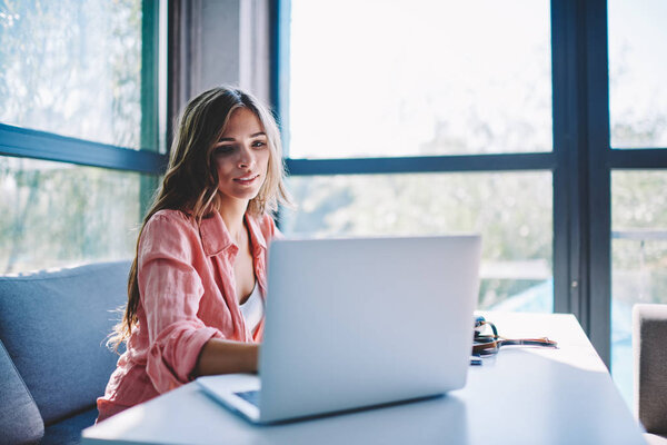 Обаятельная молодая женщина смотрит интересный веб-бинар на веб-сайте, используя беспроводное подключение к Интернету на ноутбуке в кафе.
