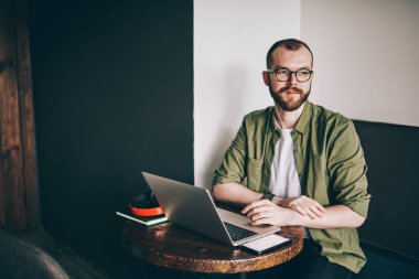 Durulması hipster freelancer gözlük vizyon düzeltme uzak adlı kafede modern dizüstü bilgisayar çalışırken seyir için içinde sakallı. Düşünceli genç adam bilgisayarda kablosuz internet kullanarak yazılım güncelleme