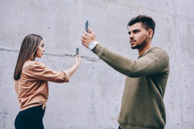 Erkek ve dişi hipsters, yüzlerini sosyal ağlar iletişim için bağımlısı önünde akıllı telefonlar ile yürüme blogcular cep telefonu kamera çekim video birbirlerine geçen süre görmezden