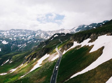 Kuş bakışı yolun bulutlu gökyüzü altında karlı dağlarda. Havadan görünümü adı Grossglockner yüksek alp yolu ile Avusturya doğal turistik rota. Hochtor geçiş parçası üzerinde hareket autobus