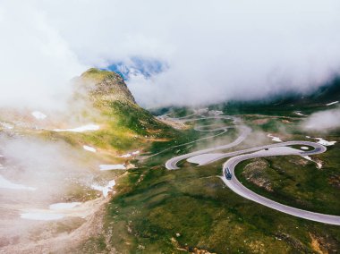 Kuş bakışı yılan kıvrımları. Avusturya 'da Grossglockner High Alpine Road adlı manzaralı bir rota. Hochtor Geçidi 'nin bazı virajları. Bulutlu gökyüzü ve karlı dağlar