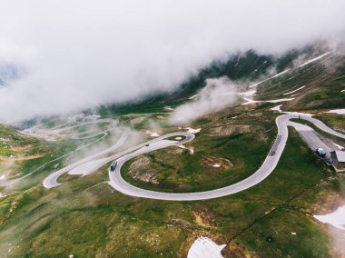 Kuş bakışı yılan kıvrımları. Avusturya 'da Grossglockner High Alpine Road adlı manzaralı bir rota. Hochtor Geçidi 'nin bazı virajları. Bulutlu gökyüzü ve karlı dağlar