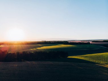Gün batımında buğday tarlası olan güzel tepe vadisinin havadan manzarası. İtalya 'nın ünlü kültürel bölgesinin kırsal arazisi, öğleden sonra gölgeleriyle Toskana toprakları