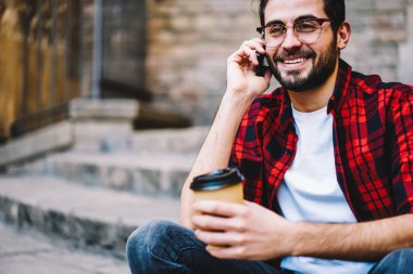 Arkadaş iletişim, kahve ile sokakta cep telefonu konuşmayı mutlu genç adam için uluslararası dolaşım normal kullanarak arama gözlükler neşeli hipster biri kırpılmış görüntü