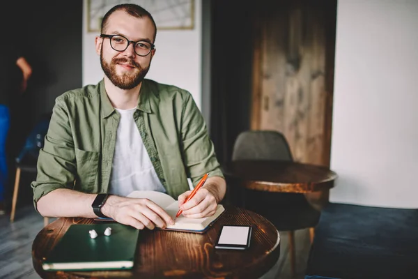 Retrato Blogueiro Masculino Sucesso Óculos Sorrindo Para Câmera Enquanto Escreve — Fotografia de Stock