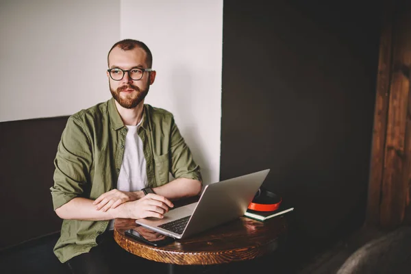 Ragazzo Barbuto Pensieroso Occhiali Guardando Altrove Mentre Lavora Computer Portatile — Foto Stock