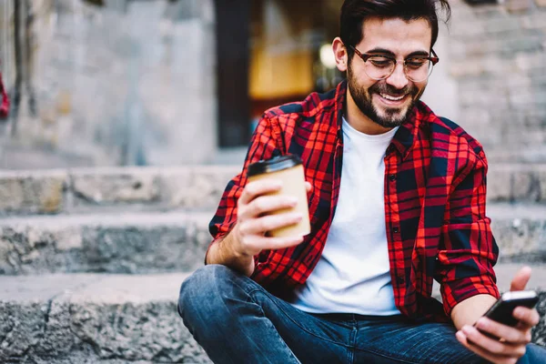 Cropped image of cheerful young man excited with sales in web store checking notification on mobile phone ,smiling male blogger browsing video on telephone and chatting with followers outdoors