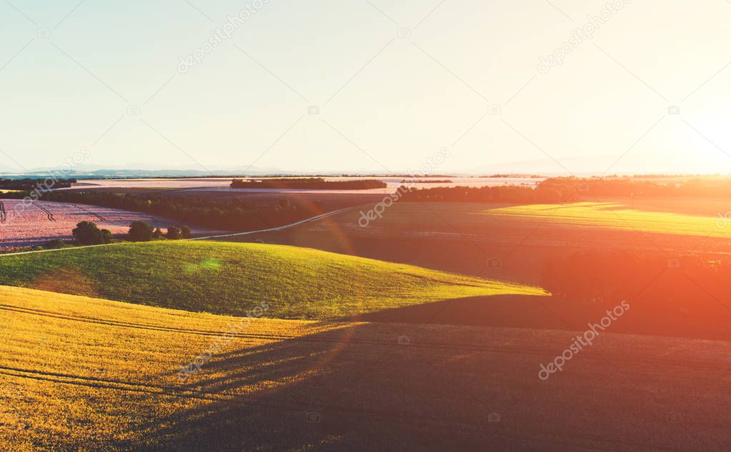 Aerial scenic view of beautiful hilly valley with wheat field at sunset time. Countryside rural landscape of famous cultural Italy region, Tuscany fields with afternoon shadows