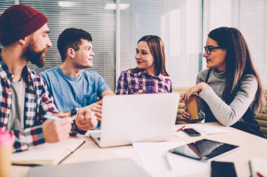 Gençlerin Giyim Tasarım proje üzerinde işbirliği modern ofis toplantıda beyin fırtınası sırasında. Erkek ve kadın çalışanların laptop ile masada oturan başlangıç için yaratıcı fikir tartışıyor