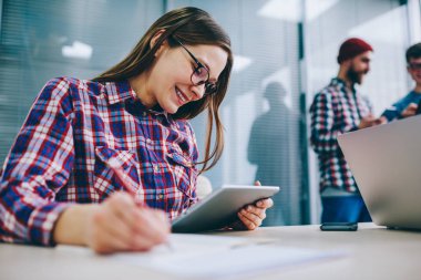 Başarılı öğrenci bilgi web sitesinde dokunmatik yüzey üzerinde okuma ve yazma aşağı notları seminer eğitimi için hazırlanıyor süre gülüyor gözlük. Ödev tablet kullanan olumlu hippi kız