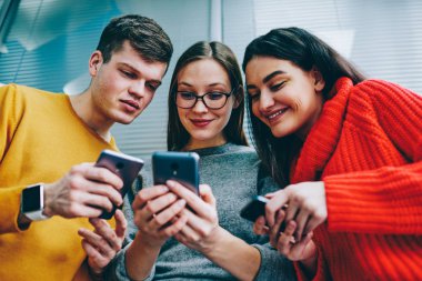 Mutlu gençler rahat kıyafet içinde blog smartphone aygıt üstünde komik video izlerken gülmekten görünümünü. Olumlu arkadaş kullanarak bluetooth bağlantısı ve 4 g telefonlar üzerinde medya paylaşma Internet