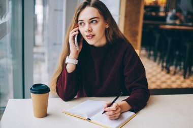 Cep telefonu aracılığıyla ise kahve dükkanında oturmuş ve penceresine, ciddi kadın yolu ile cellphone önemli laf olsun diye bakarak planlama toplantı ve görüşme için çağırıyor kadın gazeteci konsantre