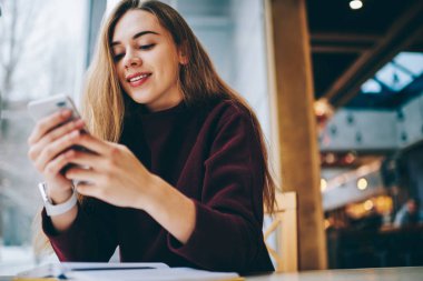 Akıllı telefon elinde tutan ve 4 g cep telefonu aracılığıyla kapalı kablosuz bağlı metin mesajı yazmaya mutlu hippi kız üniversite rahat kafeteryada, istirahat sırasında sohbet Kafkas pozitif kadın